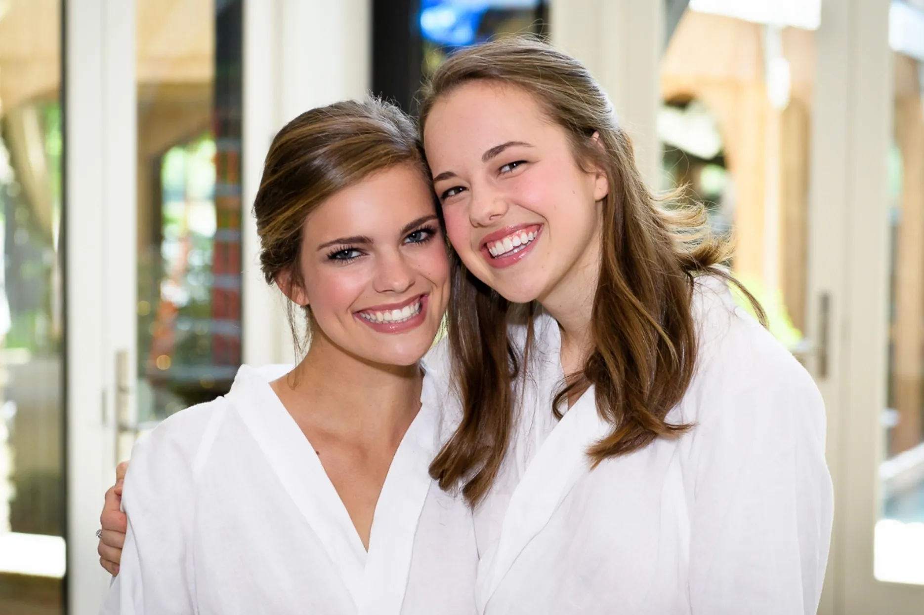 Two women in white shirts smiling for a picture.