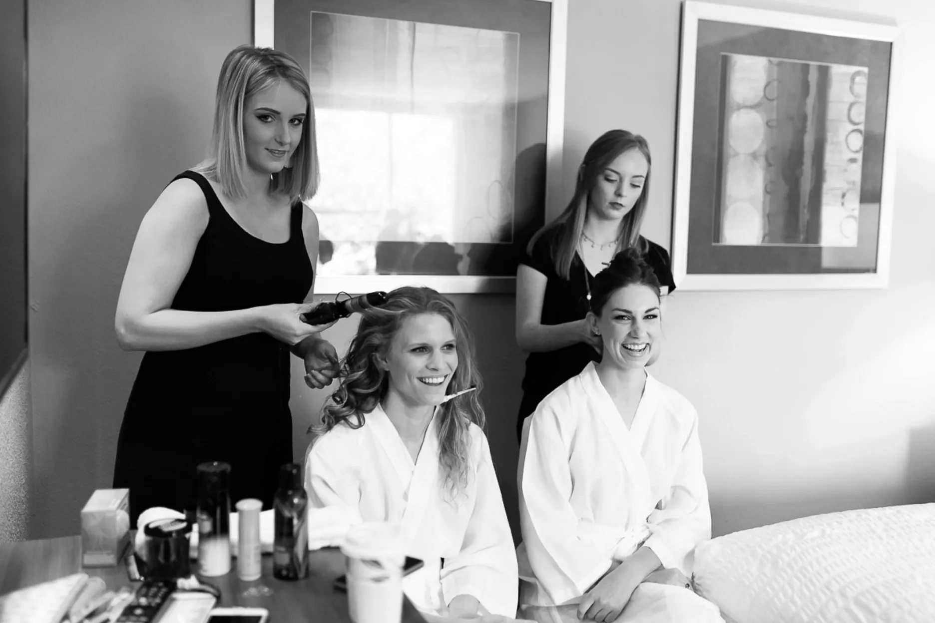 A woman is getting her hair done by two other women.