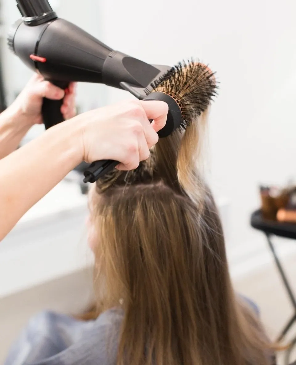 A woman blow drying her hair in the salon.