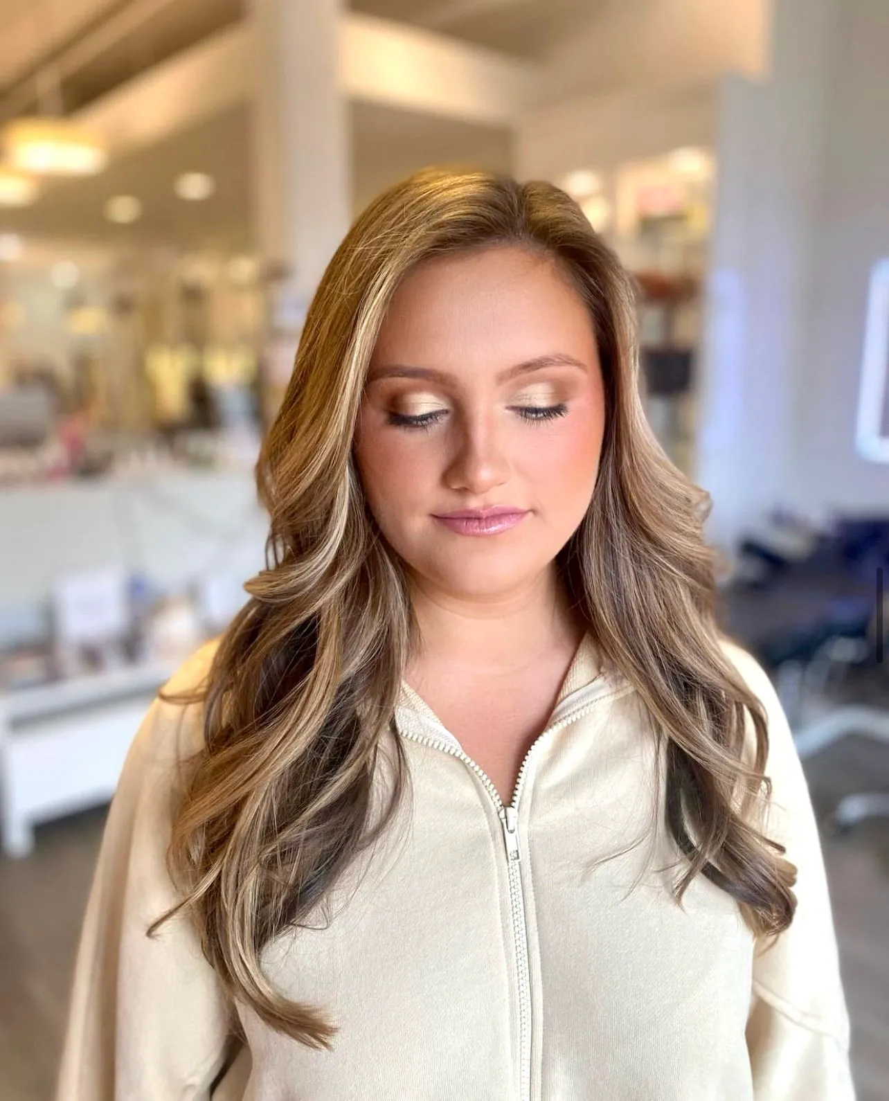 A woman with long hair and makeup in a room.