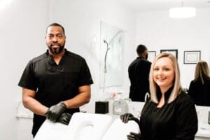 Two people standing in a room with some hair products.