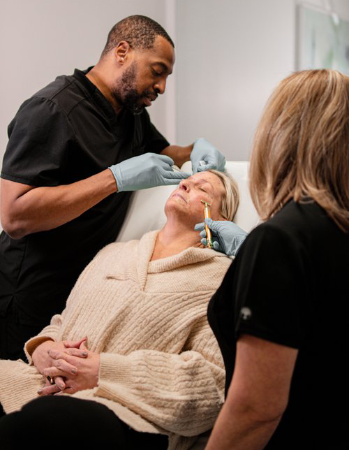 A woman getting her face waxed by two men.