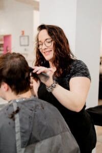 A woman is cutting another person 's hair