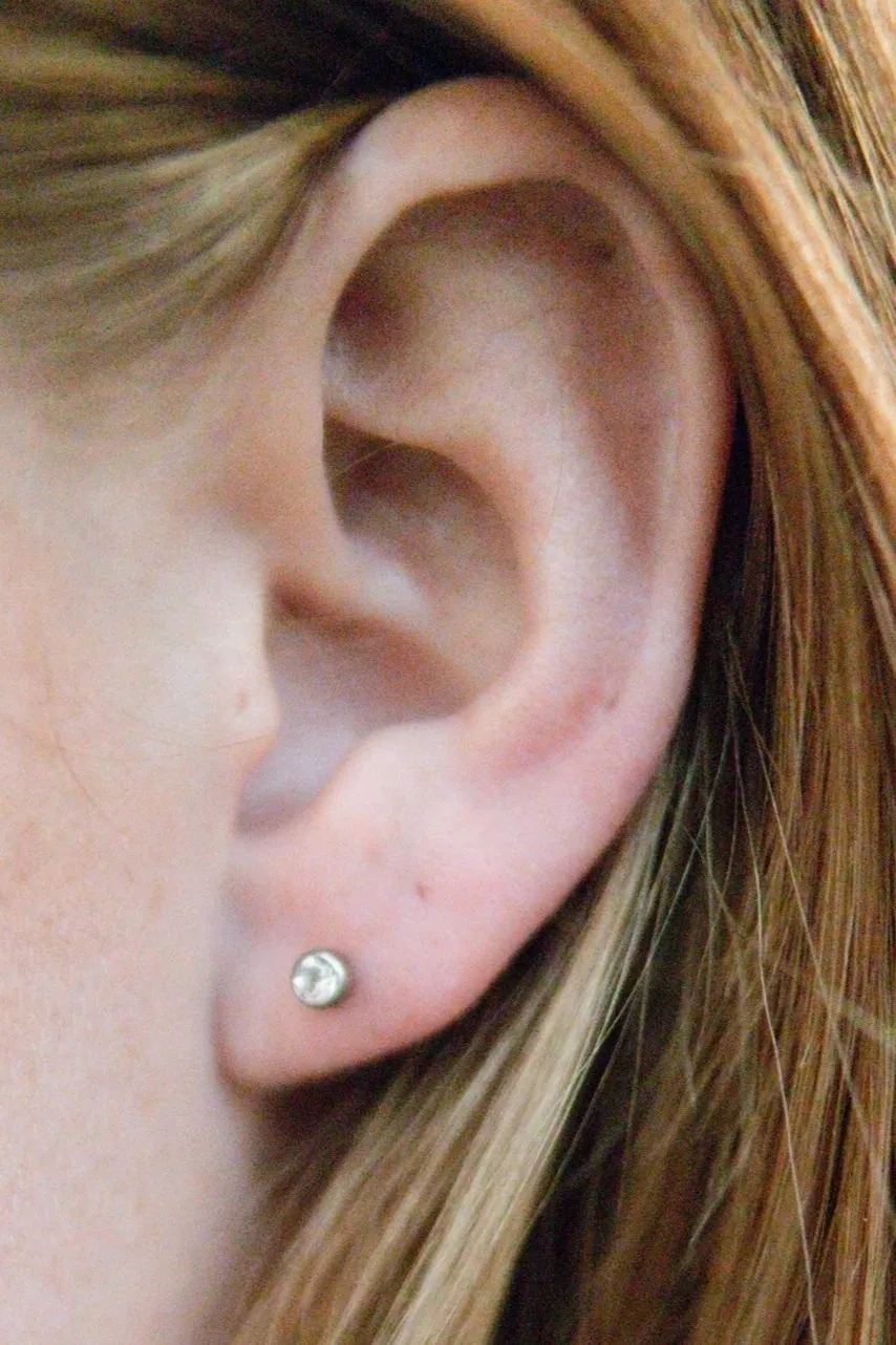 A close up of the ear with a diamond earring.