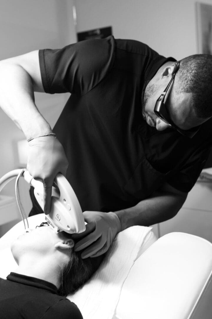 A man is shaving his face with an electric razor.