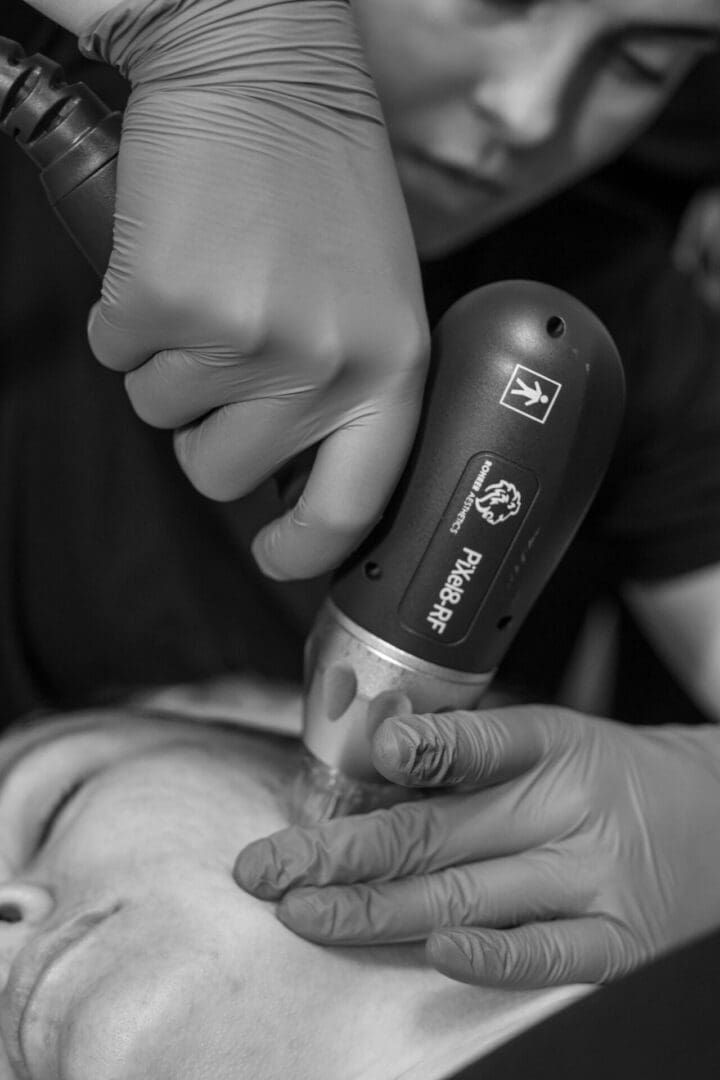 A person using an electric razor on another person 's face.