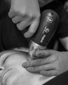 A person is using an electric hair dryer on another person 's face.