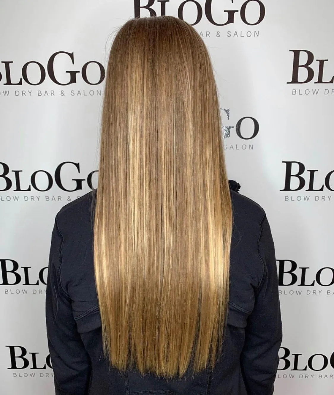 A woman with long blonde hair standing in front of a wall.