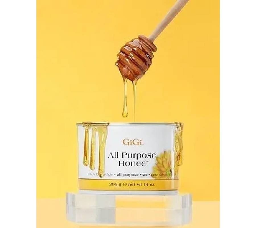 A person is pouring honey from a wooden stick into a glass.