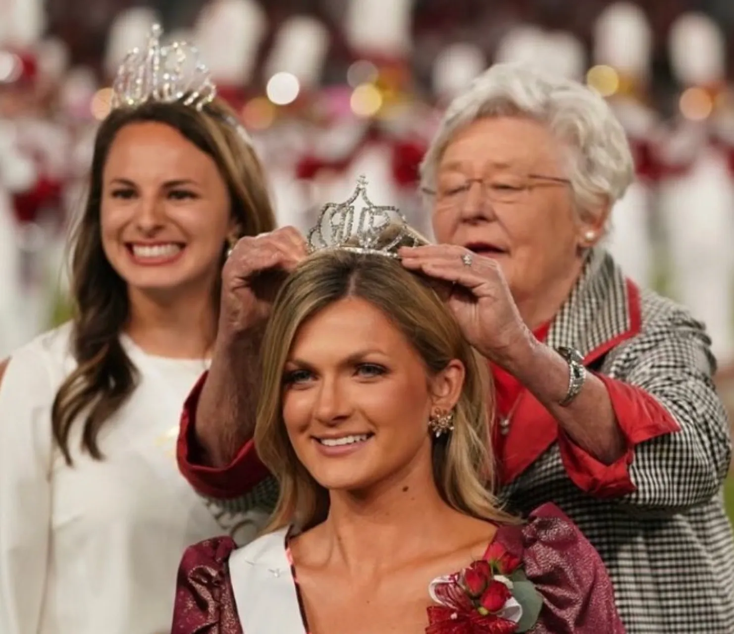 A woman is getting her crown put on by two other women.