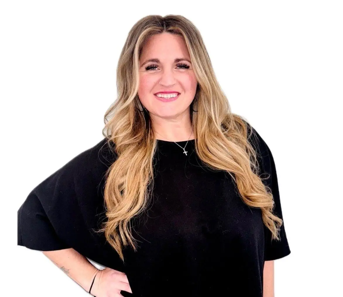 A woman in black shirt standing next to white wall.