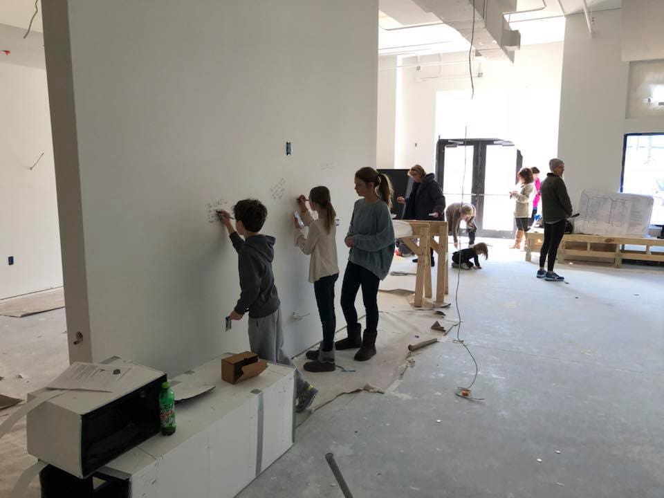 A group of people standing in front of a wall.