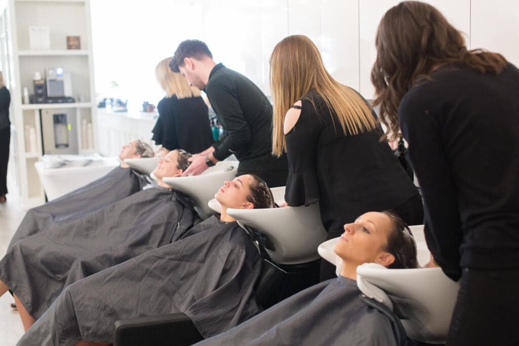 A group of people sitting in chairs with hair dryers.