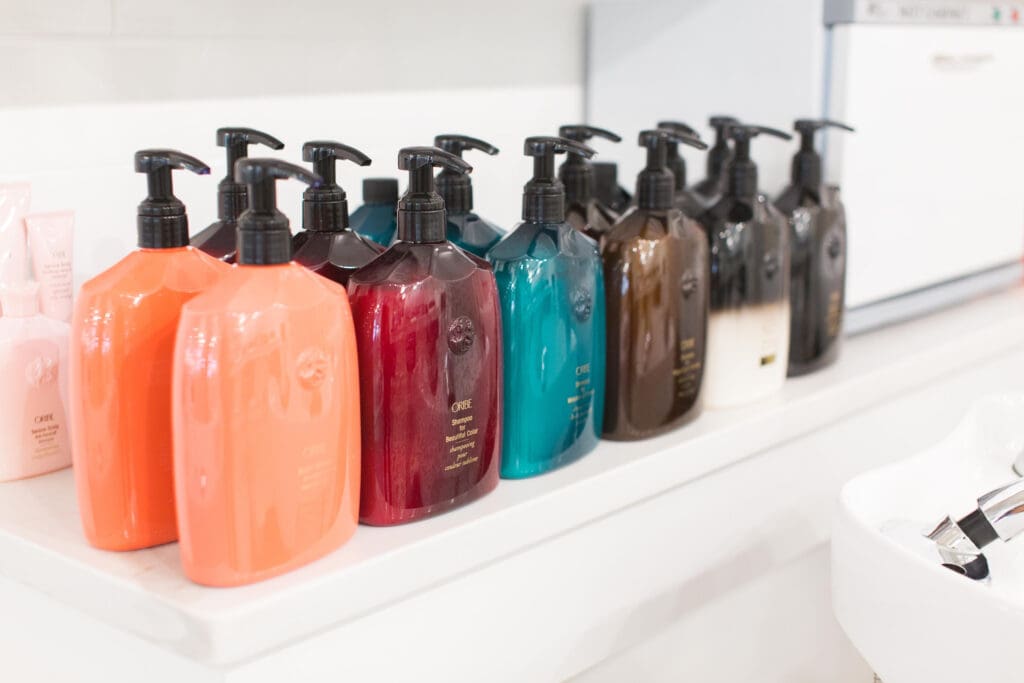 A shelf with many different colored bottles of soap.