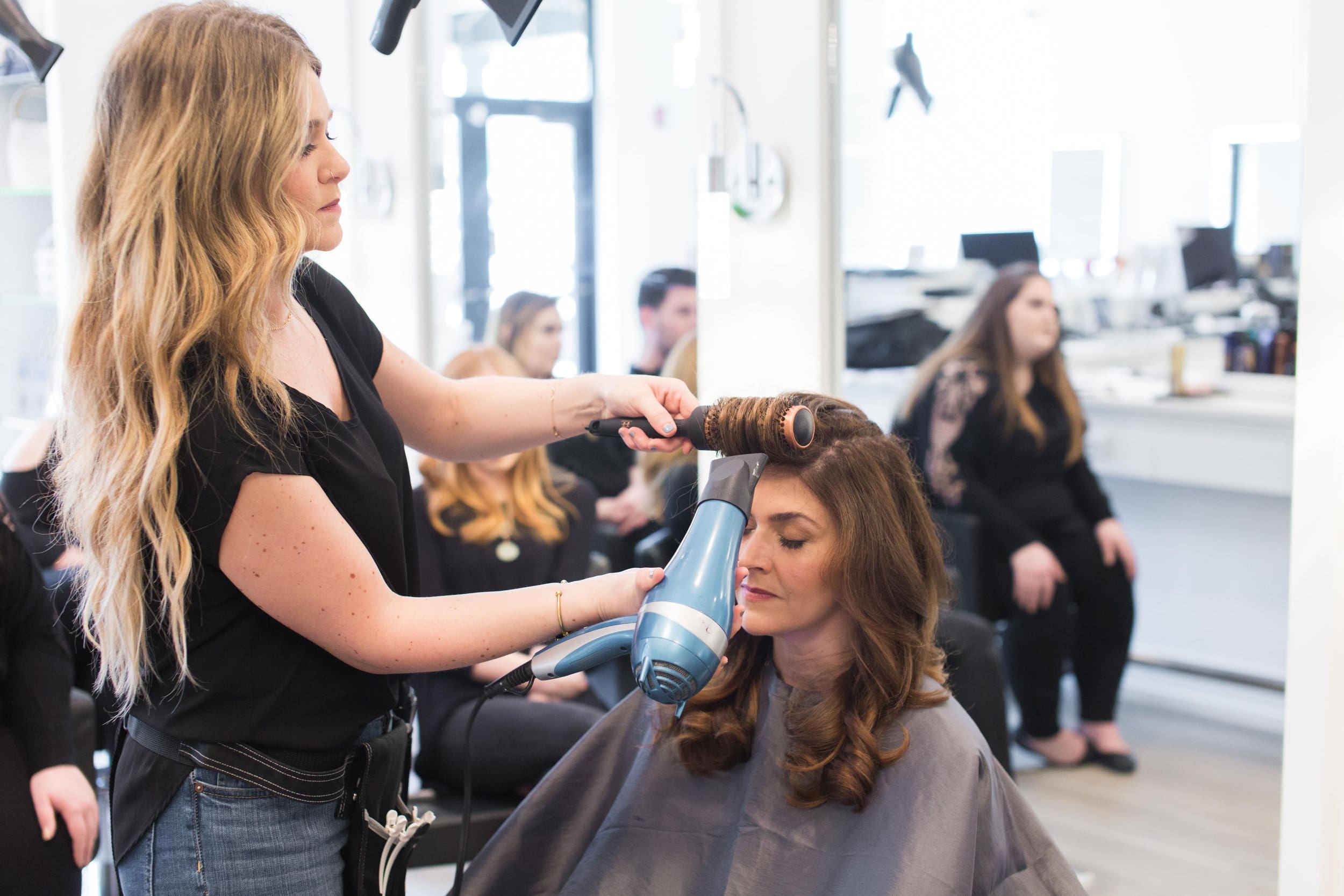 A woman blow drying another woman 's hair.