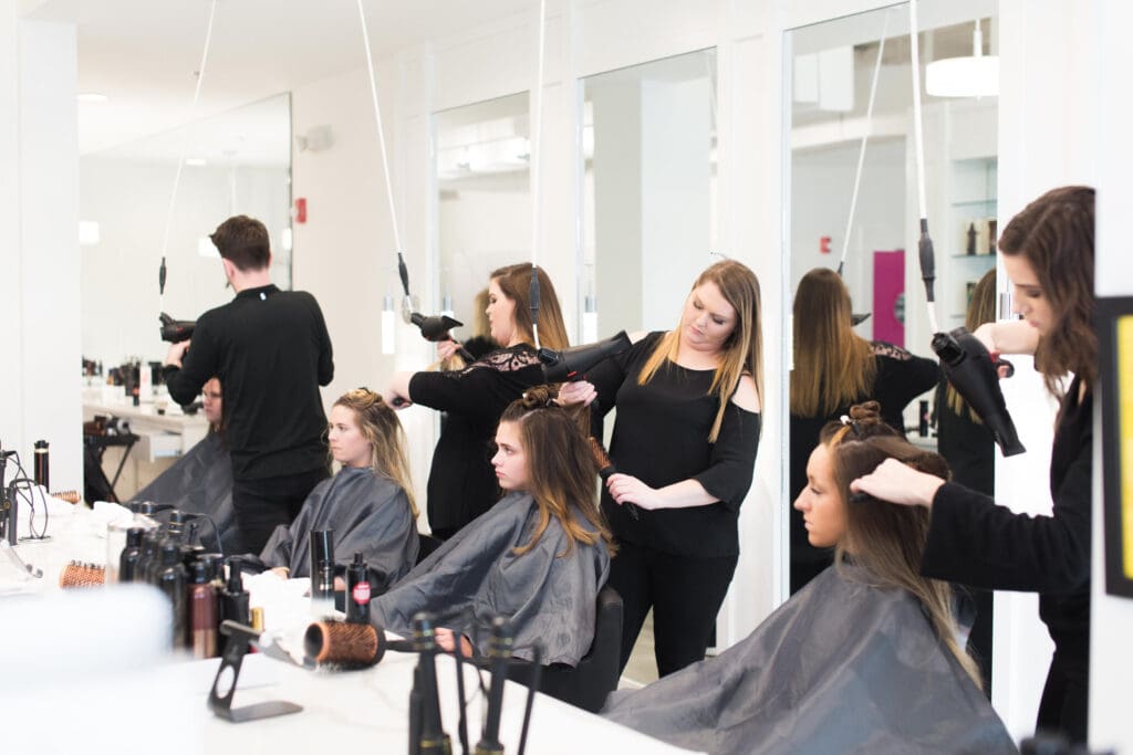 A group of people in black shirts blow drying their hair.