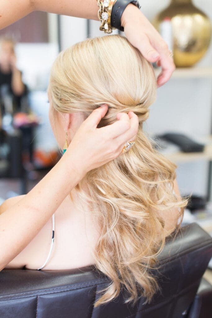 A woman is putting her hair in the back of her head.