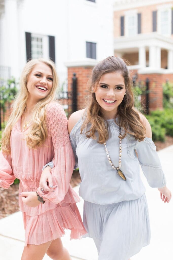 Two women in dresses are smiling for the camera.