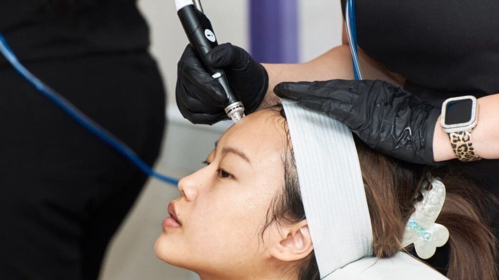 A woman getting her hair cut by an esthetician.