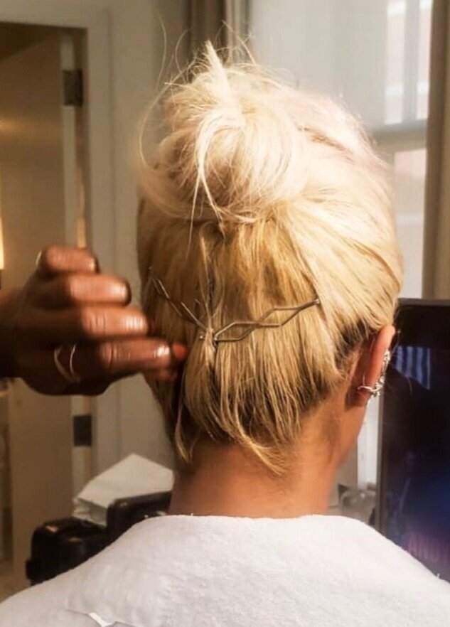 A woman is fixing her hair with some scissors.