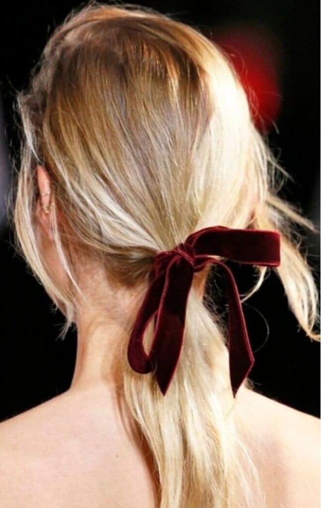 A woman with blonde hair wearing a red bow.