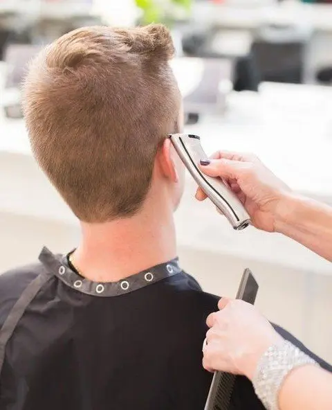 A man getting his hair cut by another person.