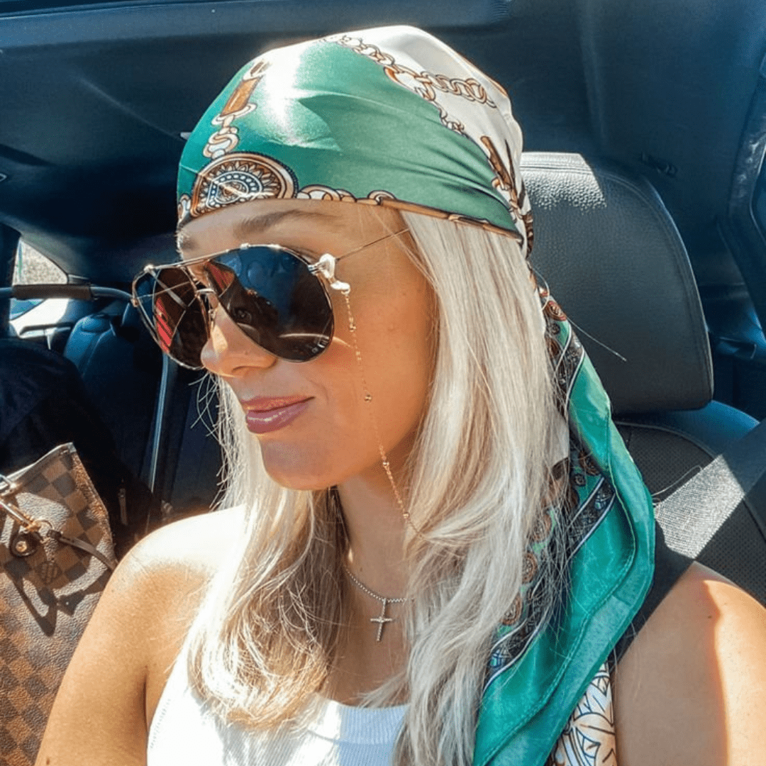 A woman with sunglasses and a head scarf.