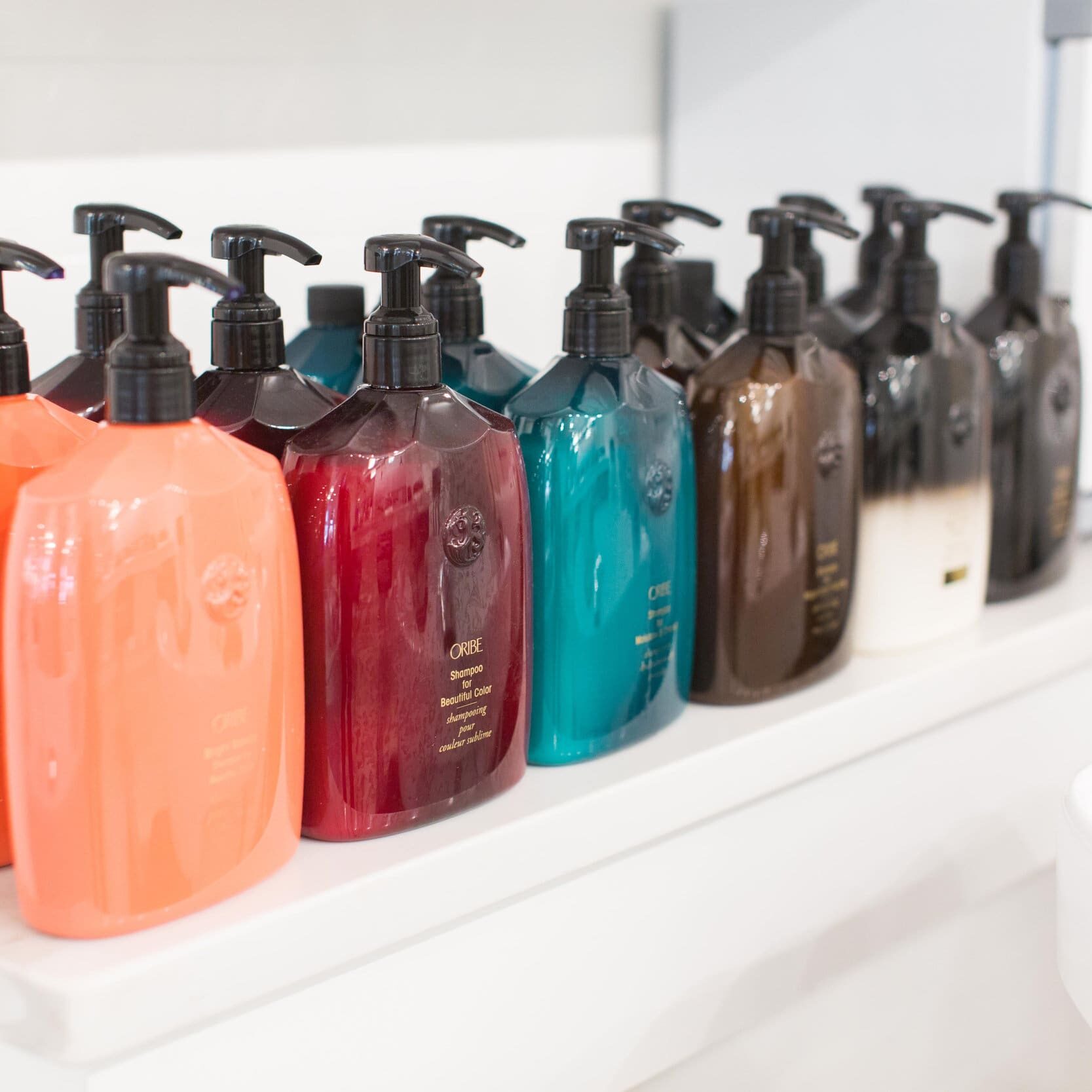 A shelf with many different colored bottles of soap.