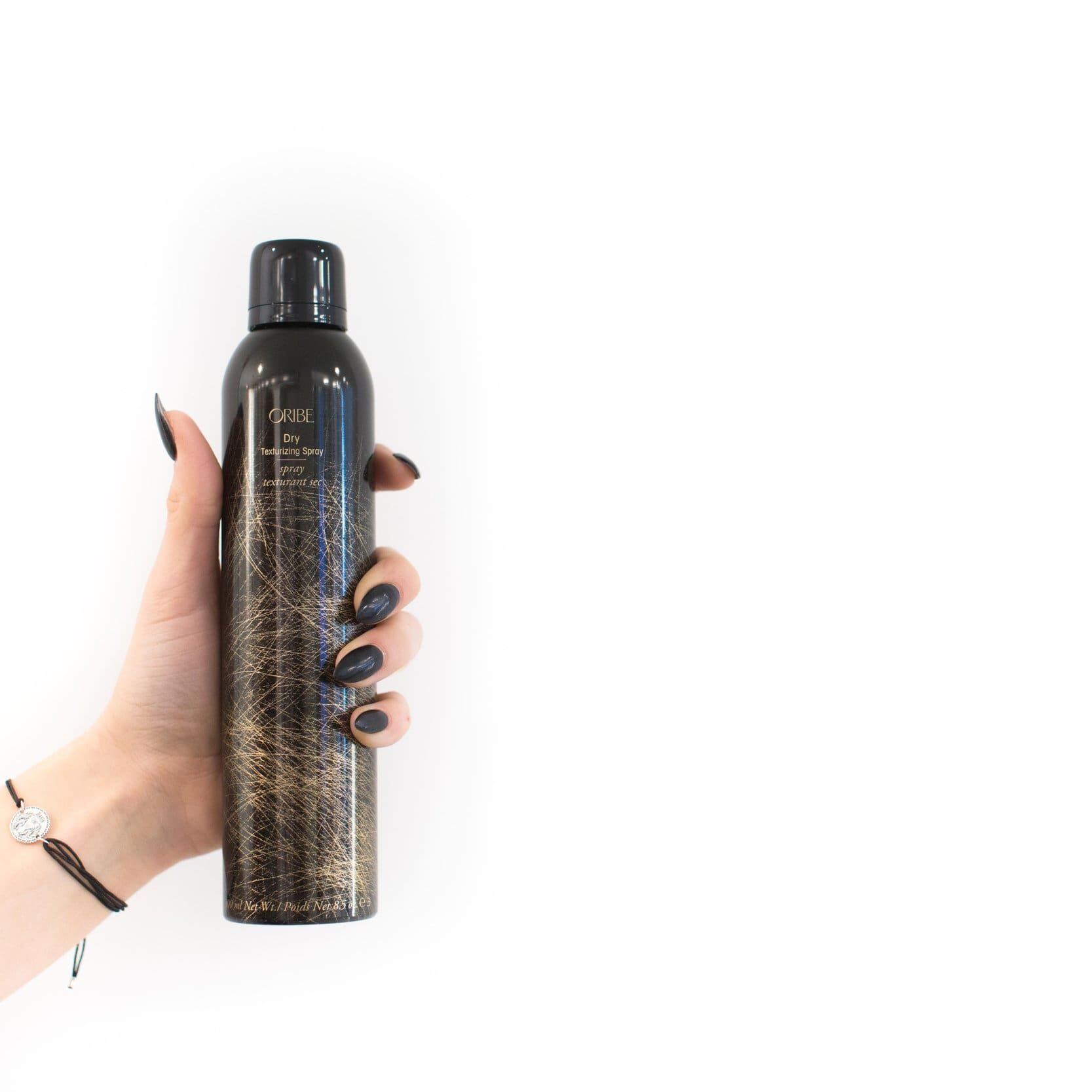 A person holding a bottle of hair spray.